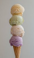 Stacked scoops of colorful ice cream in waffle cone featuring orange, pistachio, peach and berry flavors against neutral background. Refreshing summer dessert.