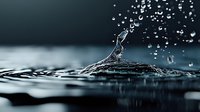 Dramatic water drop collision creating crown splash formation with floating droplets against dark background, captured in high-speed macro photography.