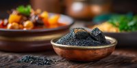 Black caviar served in copper bowl on rustic wooden table with blurred gourmet dishes in background, luxury appetizer presentation in restaurant setting.