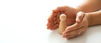 Protective hands cupping wooden figure symbolizing care, security and human resources management on white background for business concepts.