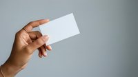 Close-up of hand holding blank white card against neutral background, suitable for business branding, marketing mockups, and corporate identity design.