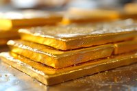 Stacked gold bars with selective focus showing metallic texture and reflective surface in warm lighting, representing wealth, investment and financial security.