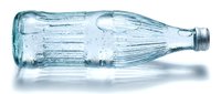Empty clear glass bottle lying on side with ribbed texture design isolated on white background for packaging and beverage industry applications.