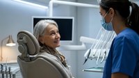 Senior woman patient receiving consultation from female dentist in modern dental office with professional equipment and comfortable treatment chair.