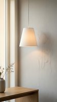 Minimalist pendant lamp with cream fabric shade hanging above wooden table in bright, neutral interior space with natural window light and dried flowers.