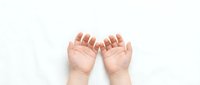 Baby hands reaching up on white background showing tiny fingers and palms in gentle gesture for parenting and childcare concepts.