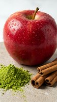 Fresh red apple with water droplets, cinnamon sticks and matcha powder on stone surface for healthy food and wellness content.