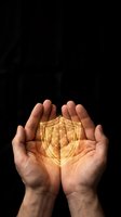 Hands holding glowing golden shield symbol against dark background, representing security, protection, and digital safety for cybersecurity and insurance concepts.