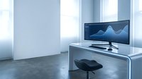 Minimalist modern office with ultrawide monitor displaying data analytics charts on a sleek white desk in a bright workspace.