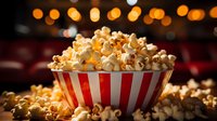 Fresh popcorn overflowing from classic red and white striped bowl against dark background with golden bokeh lights, perfect for cinema and entertainment concepts.