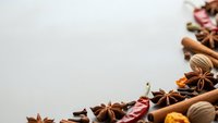 Aromatic spices and herbs arranged on neutral background with copy space for culinary designs, cooking blogs, recipe cards and food packaging.