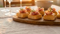 Elegant appetizers with prosciutto and rosemary on puff pastry served on wooden board, perfect for entertaining, dinner parties, and gourmet catering events.