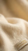 Soft beige cashmere sweater with luxury fabric texture and warm lighting for fashion and textile design projects.