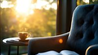 Cozy morning atmosphere with coffee cup on side table next to blue tufted armchair, golden sunlight streaming through window creating warm bokeh effect.