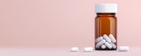 White pharmaceutical pills scattered near amber prescription bottle on pink background, minimalist medical composition for healthcare concepts.