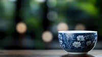 Blue and white ceramic bowl with floral pattern on wooden table against blurred green garden background for kitchen decor and dining concepts.