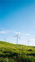 Wind turbines on rolling green hills with wildflowers under clear blue sky, representing renewable energy and sustainable power generation for environmental and industrial applications.