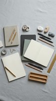 Minimalist office supplies and stationery items arranged on marble surface including notebooks, pens, pencils, erasers and wooden organizer for workspace design.