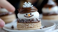 Festive winter macaron decorated as cheerful snowman with chocolate ganache, white cream filling, and sparkling sugar crystals on delicate plate.