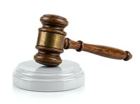 Wooden judge gavel with brass band resting on white circular base, symbolizing law, justice, authority, and legal decisions for courtroom and legal profession concepts.