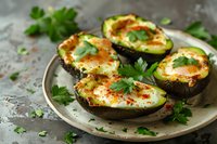Baked avocado halves with eggs and fresh herbs on rustic plate, healthy breakfast or brunch dish with parsley garnish for ketogenic diet and clean eating.
