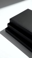 Stack of black hardcover notebooks on white surface with dramatic shadows, minimalist style for branding, stationery, and office design concepts.