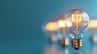 Glowing vintage light bulb with filament on blurred teal background with bokeh lights, symbolizing innovation, creativity and bright business ideas.