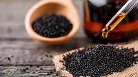 Black cumin seeds on rustic wooden background with essential oil dropper, natural medicine and spice ingredient for cooking and aromatherapy.