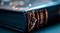 Vintage leather-bound book with ornate gold embossing on spine against blurred bokeh background, dramatic close-up macro photography in moody teal tones.