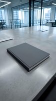 Modern office workspace with black notebook on concrete desk in corporate building interior with glass walls and city view for business presentations.