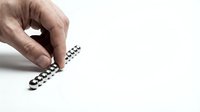 Hand arranging shiny silver magnetic balls into a line on a white surface, demonstrating physics, creativity, and precision in a minimalist setting.