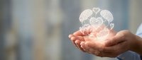 Open hands presenting glowing brain with heart symbols representing mental health awareness, emotional intelligence and psychological wellbeing concepts.