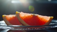 Fresh juicy orange wedges with water drops on dark background, macro shot with selective focus and natural lighting for food photography and healthy eating concepts.