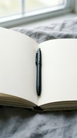 Open blank notebook with black pen on marble surface near window for writing, journaling, planning and creative work in natural light.