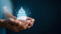 Hands holding glowing government building hologram with sparkles representing political power, democracy, civic engagement and public administration concepts.