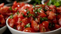 Fresh diced tomatoes mixed with chopped herbs in white ceramic bowl, close up view of homemade salsa or bruschetta topping for Mediterranean cuisine.