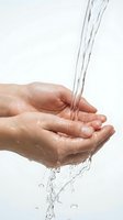 Clean fresh water flowing into cupped hands against white background for hygiene and wellness concepts.