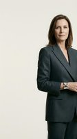 Professional mature Caucasian businesswoman in dark gray suit with crossed arms standing confidently against neutral background for corporate presentations.
