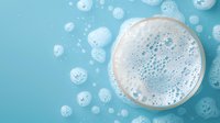 Frothy soap bubbles and foam on turquoise background viewed from above. Clean fresh white foam circles create minimalist pattern for spa and hygiene concepts.