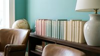 Cozy reading nook with organized bookshelf, leather armchair, and ceramic lamp in modern living room interior for home decor and lifestyle concepts.