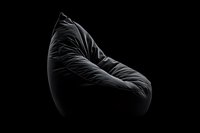Minimalist black bean bag chair with dramatic lighting and deep shadows on dark background, modern furniture design concept for contemporary interior spaces.
