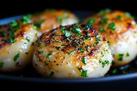 Pan seared sea scallops garnished with fresh chopped parsley and black pepper on dark plate, close up view showing caramelized golden crust and juicy texture.