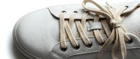 White leather sneaker close-up with tied laces, showcasing clean minimalist style for fashion, footwear, and lifestyle design projects.