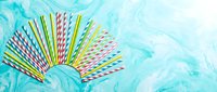 Colorful paper drinking straws spread in fan shape on turquoise marble background. Party supplies and eco-friendly alternatives for celebrations and events.