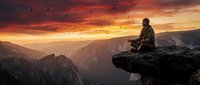 Man meditating on mountain cliff edge during dramatic sunset with birds flying overhead in peaceful wilderness landscape for mindfulness and spiritual content.