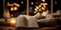 Cozy open book with candle and miniature Christmas tree on wooden table, warm knitted blanket and festive bokeh lights creating peaceful holiday atmosphere.