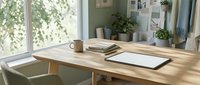 Wooden desk with notebook, coffee cup, and plants near bright window with natural sunlight for home office workspace design.
