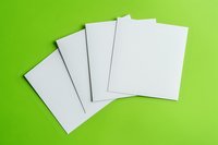 Blank white paper sheets arranged in fan layout on bright lime green background, perfect for business mockups and creative design presentations.