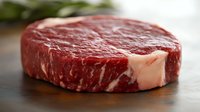Raw ribeye steak with marbling on wooden cutting board ready for grilling, cooking or barbecue preparation in kitchen setting.
