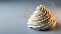 Elegant swirled white cream or frosting with golden spice powder dusting against soft gray background for culinary and dessert design projects.